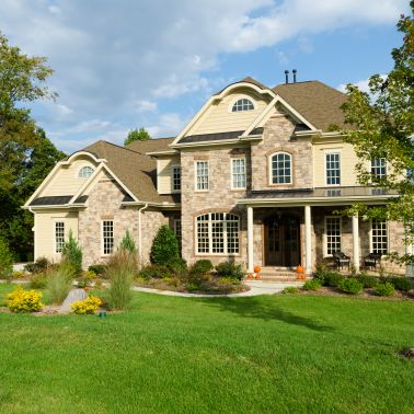 This large French Country style house has a hip roof made of shingles and a brown color. The siding is clapboard and the color is beige. It is a single family house not an apartment building. The size of the house is quite large making it a great place to live.