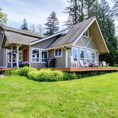 This beautiful farmhouse style home has a gray shingle roof that stands out against the bright blue sky. The shingles are made of a durable material that will last for years to come. The roof has a slight pitch that adds to the classic farmhouse look. The white siding and black shutters complete the look of this charming home.