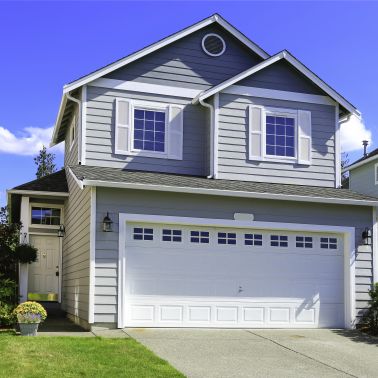 This medium-sized house has a classic gable roof painted in a dark grey color. The siding is clapboard painted in a bright blue color. The house has a traditional look with a large front porch and a few windows. It is a single-family house perfect for a small family.